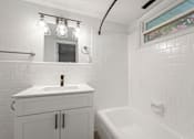 Thumbnail 7 of 10 - a white bathroom with a sink and a bath tub
