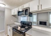 Thumbnail 9 of 19 - a kitchen with white cabinets and a stove and microwave