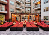 Thumbnail 18 of 26 - A patio with red sun loungers and a wooden pergola.