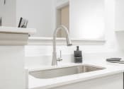 Thumbnail 36 of 41 - a white kitchen with a sink and a faucet