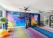 Thumbnail 6 of 31 - A colorful gym with a slide and exercise equipment.