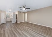 Thumbnail 6 of 17 - a living room with a ceiling fan and a kitchen in the background