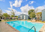 Thumbnail 33 of 38 - A swimming pool surrounded by a concrete deck and a grassy area with trees.