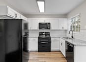 Thumbnail 47 of 54 - A black refrigerator is in a kitchen with white cabinets.