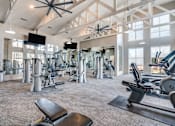Thumbnail 25 of 34 - A gym with a variety of equipment including treadmills, weights, and a bench.