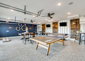 Thumbnail 24 of 34 - A ping pong table is in the middle of a room with a blue wall and a ceiling fan.