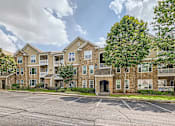 Thumbnail 2 of 37 - A large apartment complex with a parking lot in front.