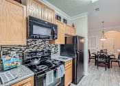 Thumbnail 10 of 37 - A kitchen with black appliances and wooden cabinets.