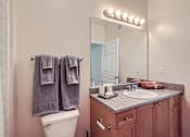 Thumbnail 20 of 37 - A bathroom with a toilet, sink, mirror, and towel rack.