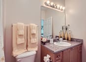 Thumbnail 24 of 37 - A bathroom with a toilet, sink, mirror, and towel rack.