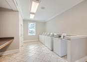 Thumbnail 23 of 37 - A row of white washing machines in a laundry room.