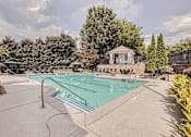 Thumbnail 26 of 37 - A large outdoor swimming pool surrounded by trees and a gazebo.