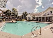 Thumbnail 28 of 37 - A large swimming pool surrounded by a concrete patio and a metal ladder.