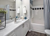 Thumbnail 12 of 25 - A white bathroom with a sink, toilet, and bathtub.