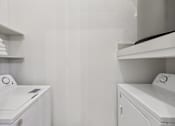 Thumbnail 16 of 38 - A white washing machine and dryer in a laundry room.
