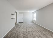Thumbnail 19 of 62 - a spacious living room with white walls and carpeting and a door to a bathroom