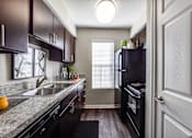 Thumbnail 14 of 62 - an empty kitchen with black appliances and granite counter tops
