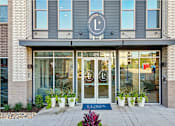 Thumbnail 25 of 26 - The entrance to a Lululemon store with a blue doormat and potted plants.