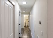 Thumbnail 11 of 40 - A long white hallway with doors on both sides and a light on the ceiling.