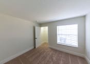 Thumbnail 8 of 40 - A room with a carpeted floor and a window with blinds.