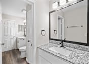 Thumbnail 44 of 54 - A bathroom with a sink, mirror, toilet and a door.