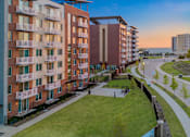 Thumbnail 30 of 31 - A sunset view of a residential area with apartment buildings and a road.