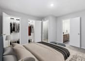 Thumbnail 5 of 22 - A bedroom with a large bed and a closet with clothes hanging.