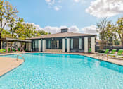 Thumbnail 1 of 38 - A swimming pool in front of a house with a sunny sky.