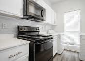 Thumbnail 12 of 33 - an all white kitchen with black appliances and white cabinets