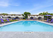 Thumbnail 19 of 23 - A 2 ft deep swimming pool with purple loungers and a fence around the pool area.