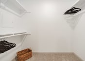 Thumbnail 20 of 35 - a walk in closet with white walls and shelves and a basket on the floor