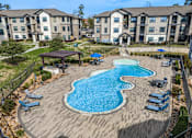 Thumbnail 15 of 28 - A large swimming pool with a wooden deck and lounge chairs.