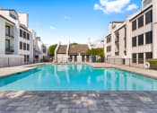 Thumbnail 22 of 28 - a swimming pool between two buildings with a blue sky in the background