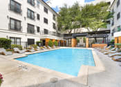 Thumbnail 20 of 37 - an outdoor pool with lounge chairs and trees in front of an apartment building