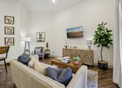 Thumbnail 13 of 38 - A spacious, open living room with expansive eggshell-colored walls and contrasting dark hardwood floors, brightly lit by natural light.