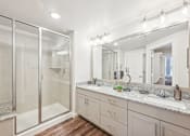 Thumbnail 22 of 34 - A bathroom with a large mirror and a walk-in shower.