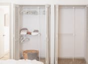 Thumbnail 11 of 34 - a walk in closet with white closet doors and a white bed with a basket