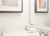 Thumbnail 14 of 34 - a bathroom with a sink and two paintings on the wall