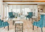 Thumbnail 22 of 34 - a living room with blue chairs and tables and a large window