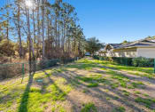 Thumbnail 27 of 30 - A backyard with a fence and a house in the background.