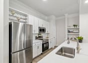 Thumbnail 3 of 42 - A modern kitchen with a stainless steel refrigerator and white countertops.