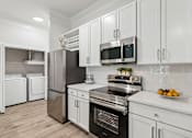 Thumbnail 4 of 42 - A modern kitchen with white cabinets and stainless steel appliances.