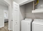 Thumbnail 12 of 42 - A white washing machine and dryer in a small laundry room.