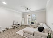 Thumbnail 7 of 42 - A living room with a grey couch and a white ceiling fan.