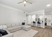 Thumbnail 6 of 42 - A living room with a grey couch and a white ceiling fan.