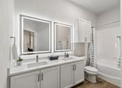 Thumbnail 10 of 42 - A white bathroom with a toilet, sink, and mirrors.