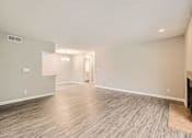 Thumbnail 7 of 22 - A spacious room with wood flooring and a doorway leading to another room.