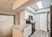 Thumbnail 4 of 22 - A kitchen with a granite countertop and white cabinets.