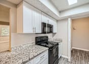Thumbnail 3 of 22 - A kitchen with a black stove top oven and white cabinets.