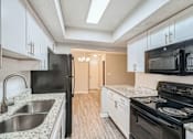 Thumbnail 2 of 22 - A kitchen with black appliances and white cabinets.
